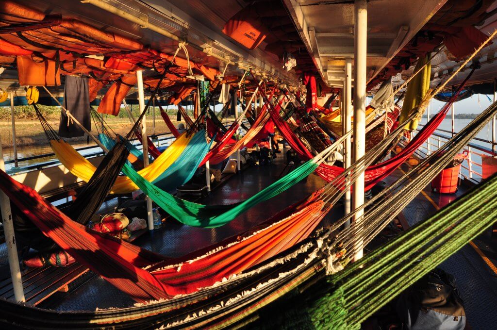 Interior de um barco no rio amazonas, cheio de redes coloridas
