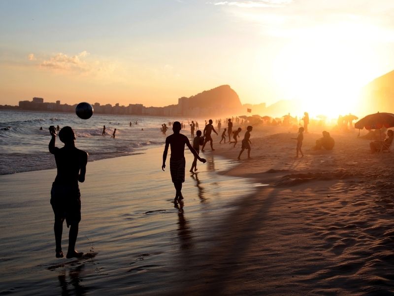 pessoas caminhando na praia no final de tarde no RJ