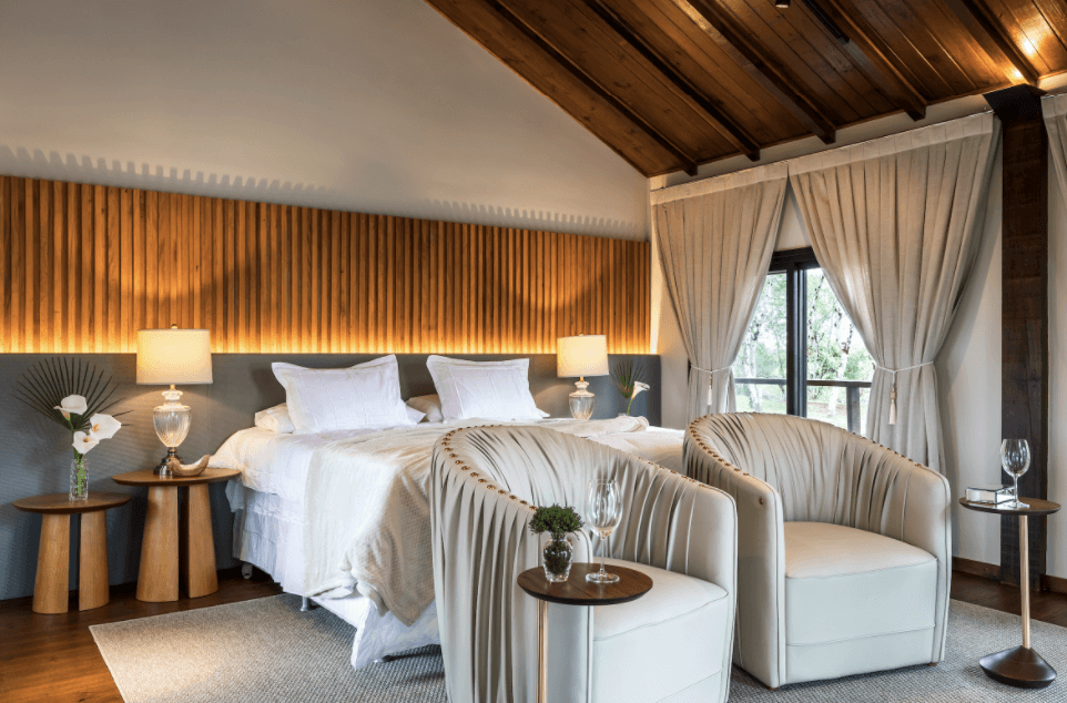 quarto de hotel com detalhes em madeira, meia luz e poltronas confortáveis