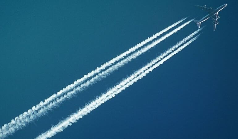 avião voando e deixando rastros de fumaça atrás dele pelos céus